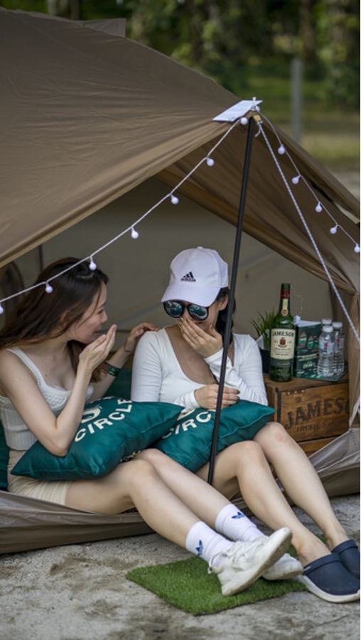 Two friends sitting in a tent at a music festival